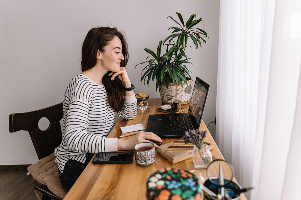 Marketer looking over influencer brief examples on her laptop at a work desk