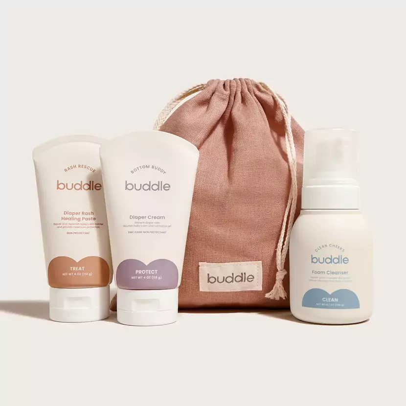 A set of three Buddle products against a plain background showcases influencer marketing at its finest. Includes a Diaper Rash Healing Paste, Diaper Cream, and Foam Cleanser. The items are accompanied by a drawstring pouch labeled buddle, driving full-funnel revenue through GRIN strategies.