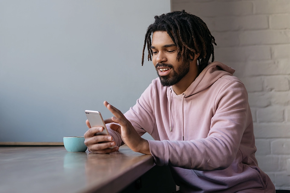Man at a table smiling at something on his smartphone