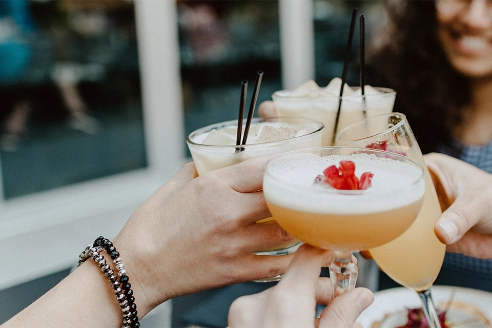 People cheering with cocktails in an example of UGC for alcohol influencer marketing