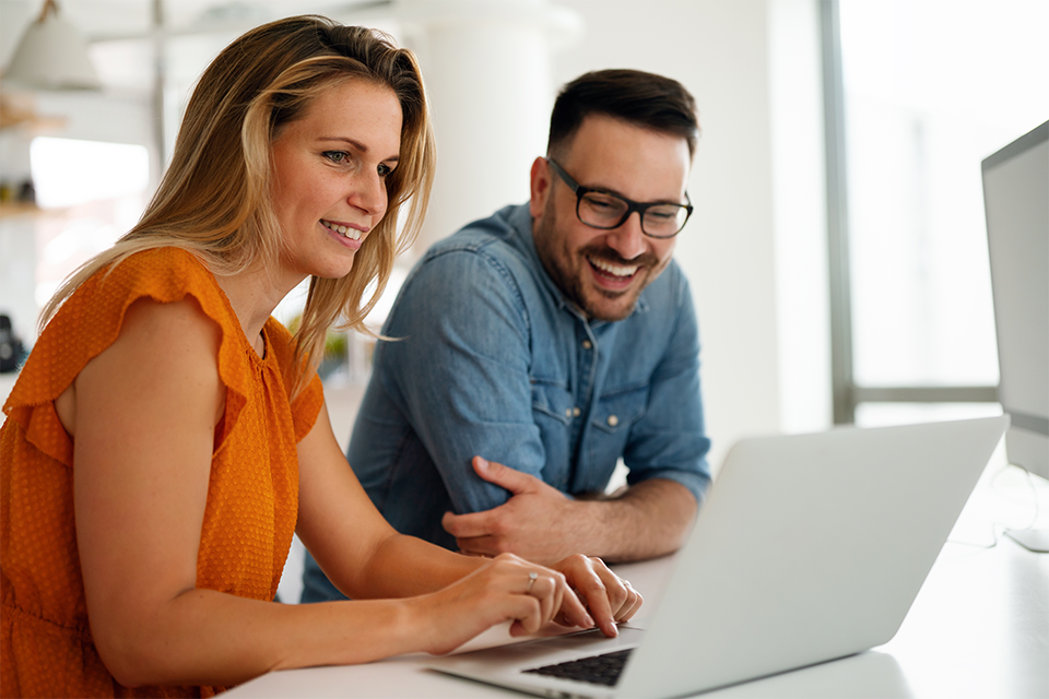 Two coworkers talking about app marketing strategies over a laptop