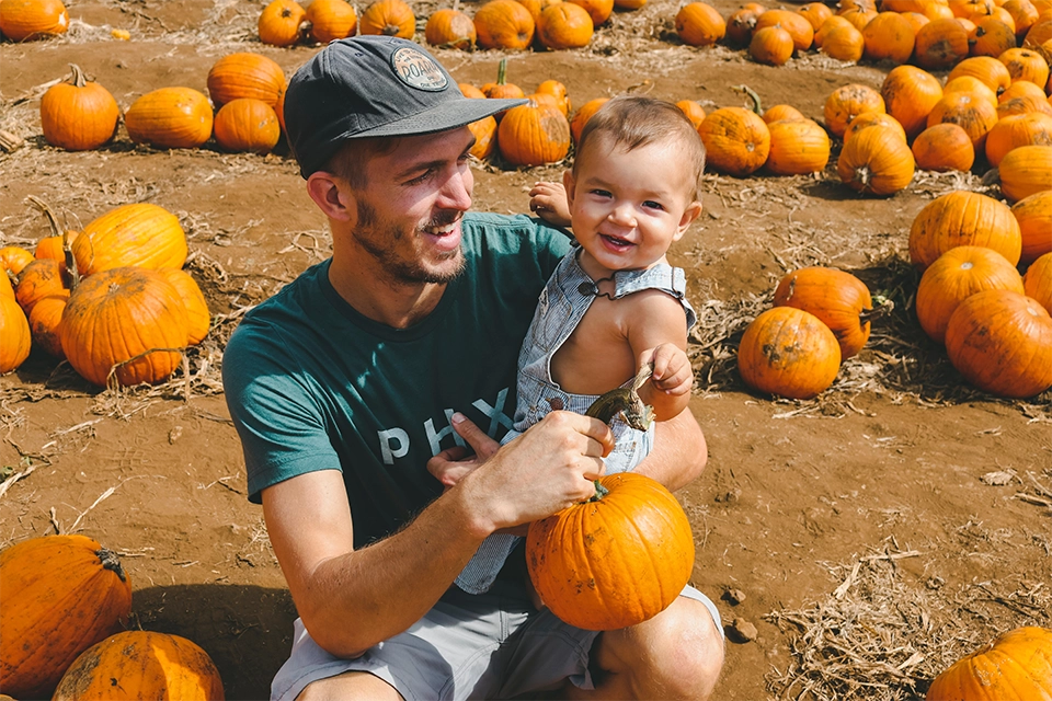 Dad influencer holding a pumpkin and a small child