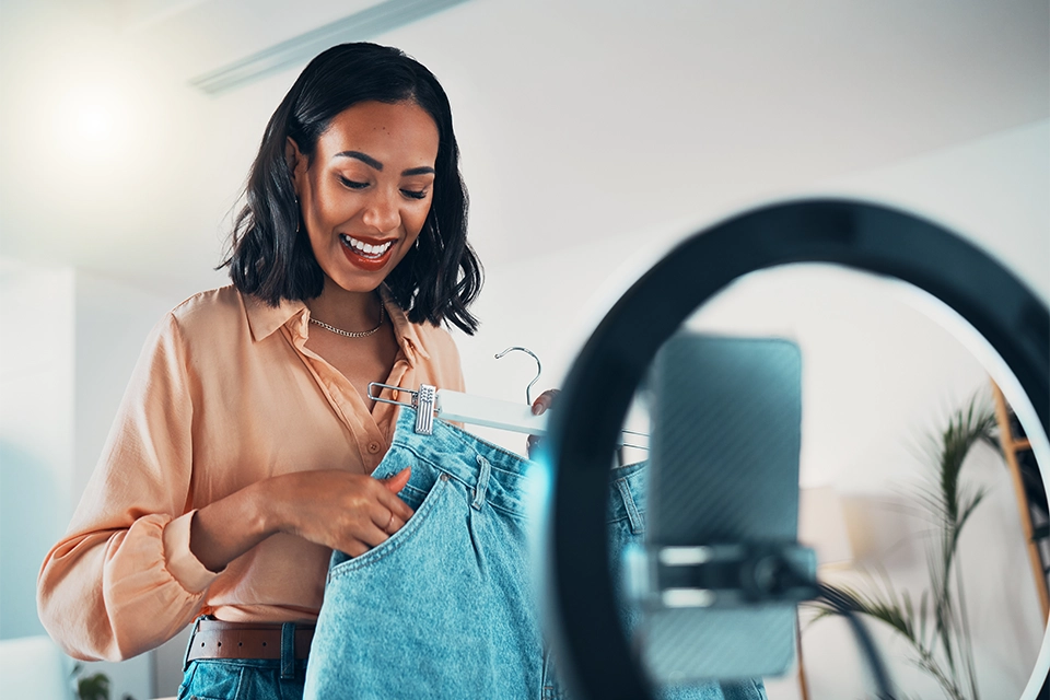 example of influencer seeding with an influencer holding a pair of gifted jeans and making a video