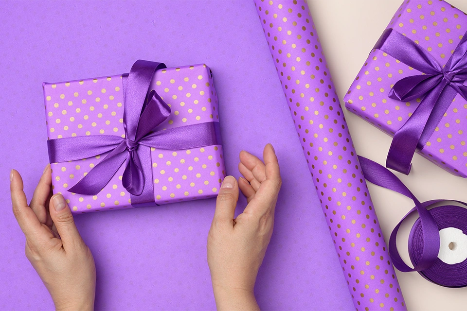 Someone wrapping a gift in purple paper