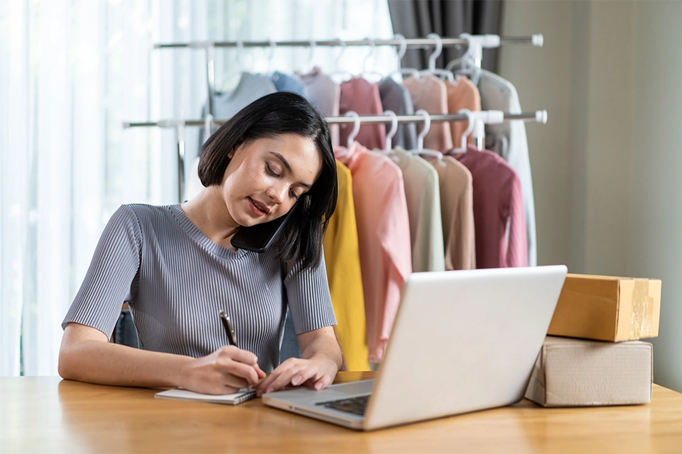 Woman working at a desk with a laptop and a pad of paper