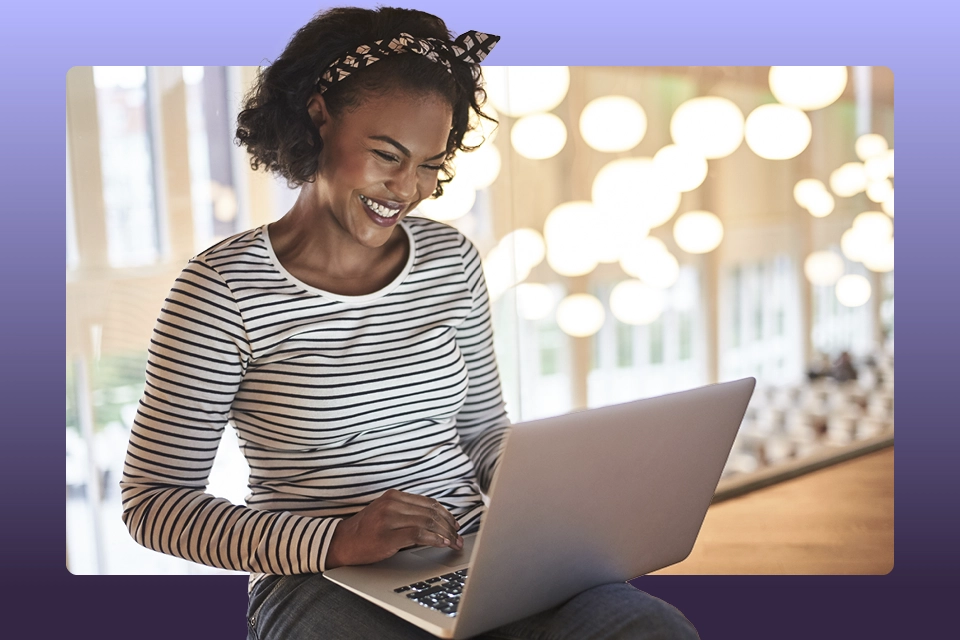 influencer smiling at a laptop as she researches how to reach out to brands as an influencer