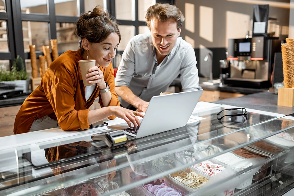 Two coffee shop owners discussing influencer marketing for small business over a laptop