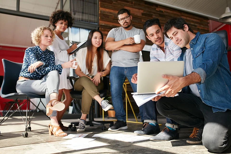 Group of people discussing influencer marketing for startups over a laptop