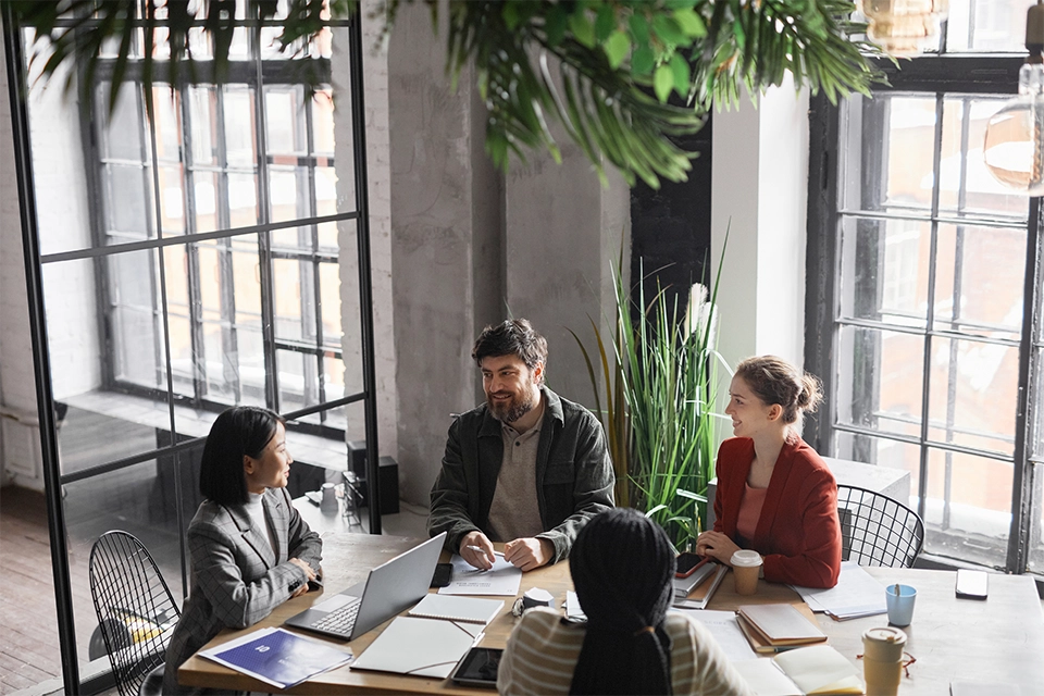 Coworkers discussing an influencer management agency vs influencer marketing software around a work table