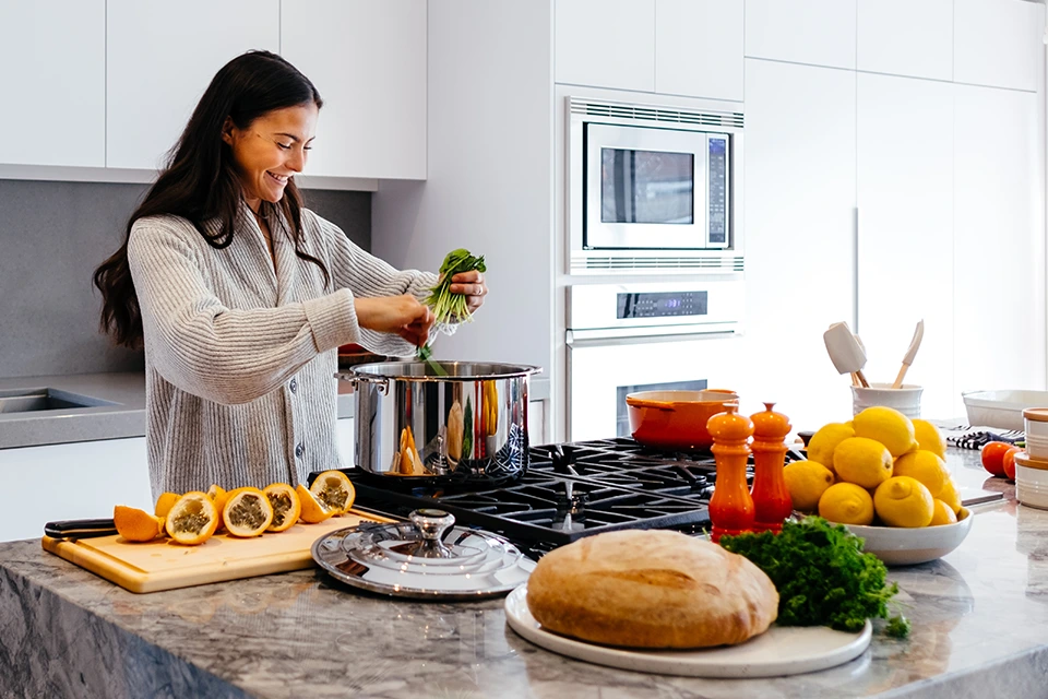 KOL (or Key Opinion Leader) woman cutting herbs over a large pot in a kitchen
