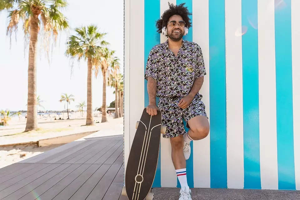 Millennial influencer with a skateboard leaning against a wall
