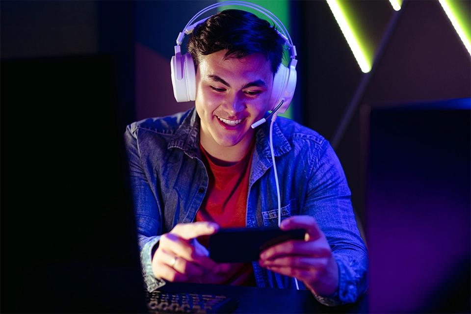 Man in headphones playing mobile games on a smartphone
