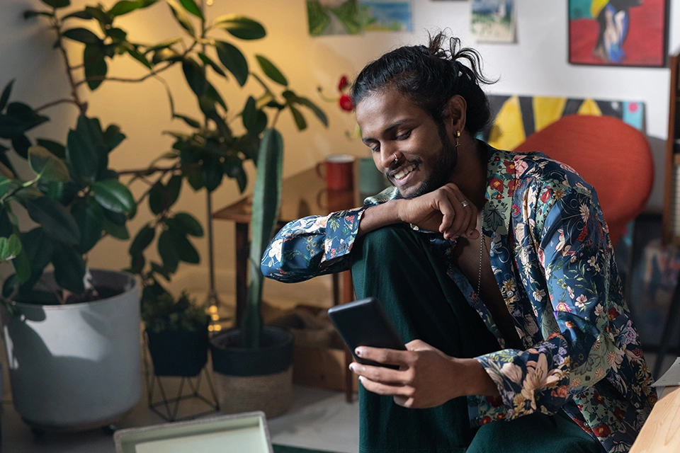 Man sitting near plants looking at his phone