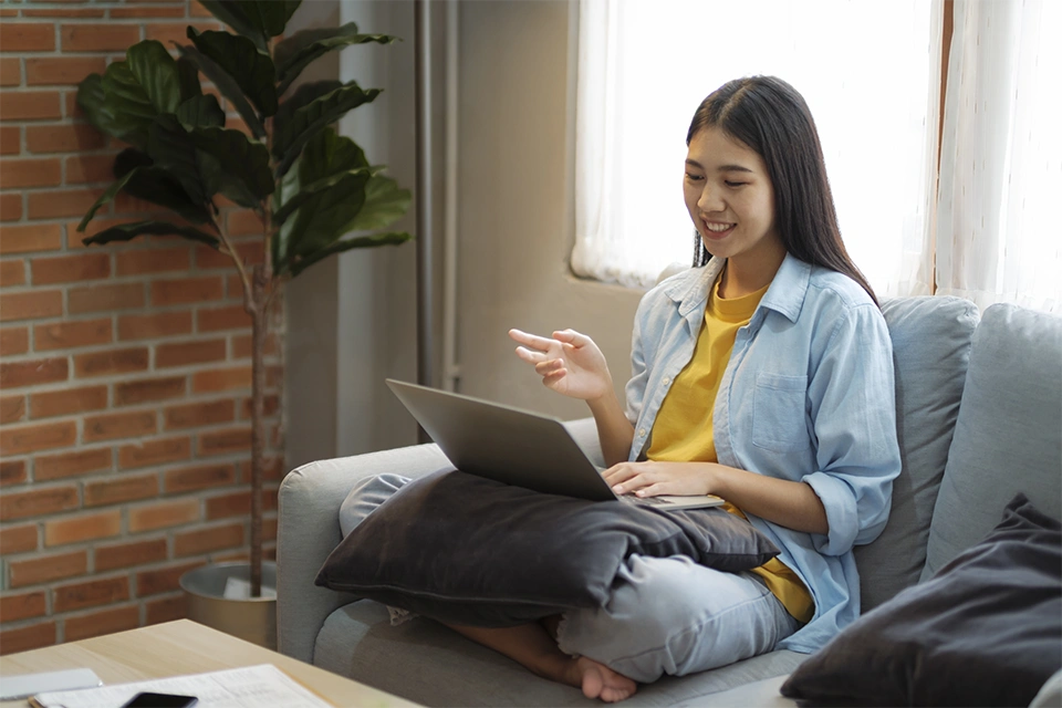 mental health influencers can be therapists that offer online therapy, like this woman sitting on a couch with her laptop