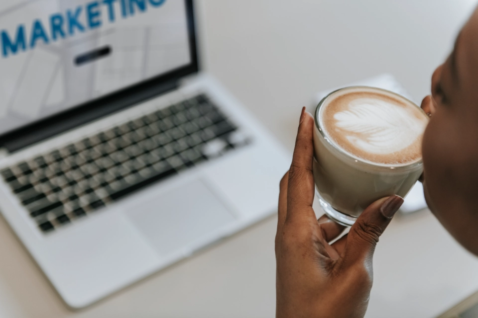 Person drinking a coffee and looking at a laptop with 